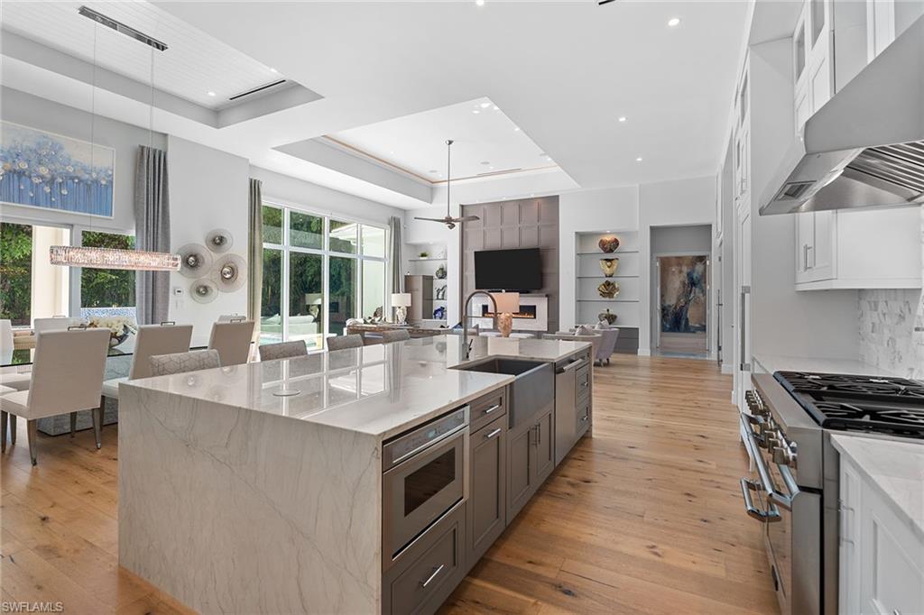 720 Orchid Drive Naples, FL 34102 - Photo 20 of 50 a large kitchen with stainless steel appliances granite countertop a lot of counter space and a wooden floor