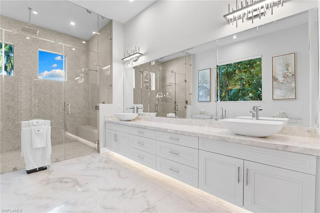 720 Orchid Drive Naples, FL 34102 - Photo 23 of 50 a bathroom with double vanity sinks a large mirror and a shower