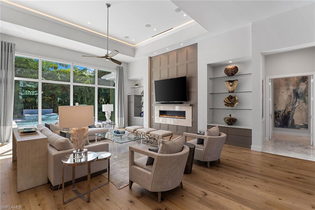 720 Orchid Drive Naples, FL 34102 - Photo 6 of 50 a living room with furniture a flat screen tv and a floor to ceiling window