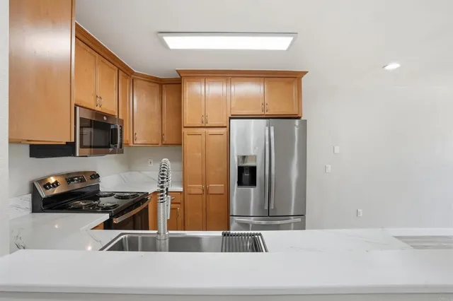 a kitchen with stainless steel appliances granite countertop a refrigerator a stove and a sink with wooden floor
