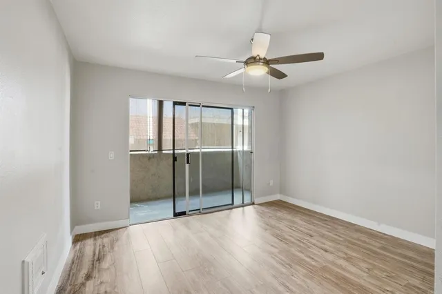 an empty room with wooden floor fan and windows