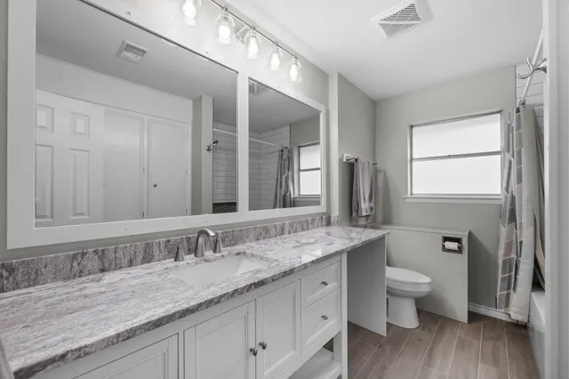 a bathroom with a granite countertop sink a toilet and a large mirror