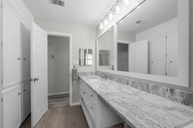 a bathroom with a granite countertop double vanity sink and mirror