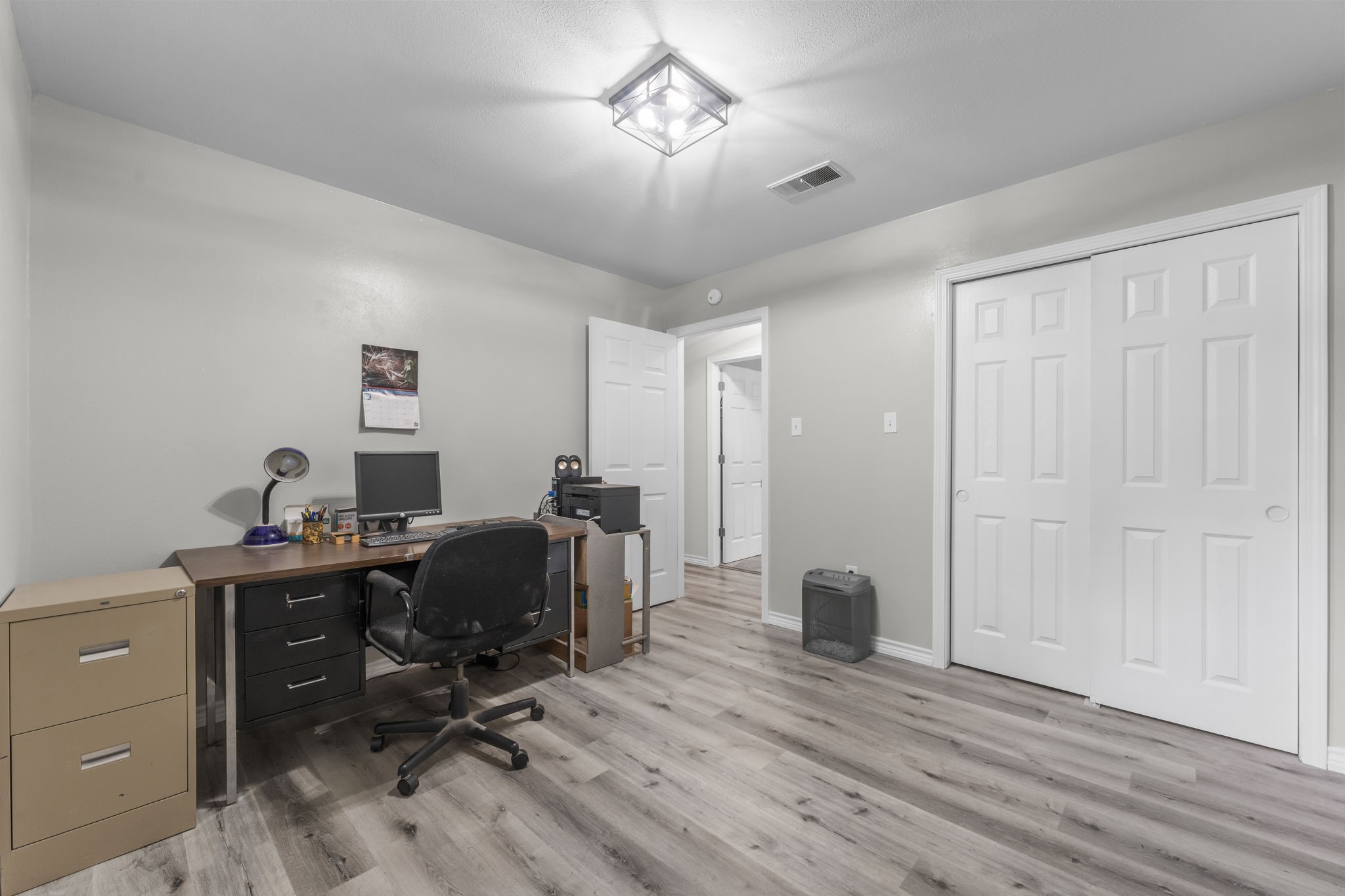 209 Summit Drive Conroe, TX 77303 - Photo 16 of 22 One of the secondary front-facing bedrooms, currently set up as a home office, showcases fresh paint, new LVP flooring, and crisp trim work; ready to fit your lifestyle.