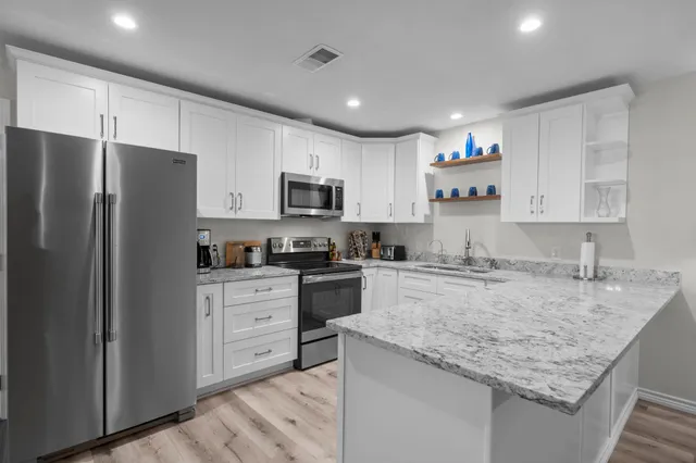 a kitchen with stainless steel appliances granite countertop a refrigerator stove microwave and sink