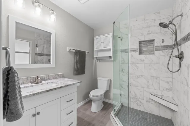 a bathroom with a granite countertop sink a toilet and shower