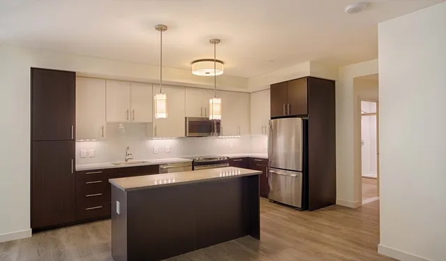a kitchen with kitchen island a counter top space a refrigerator and a sink