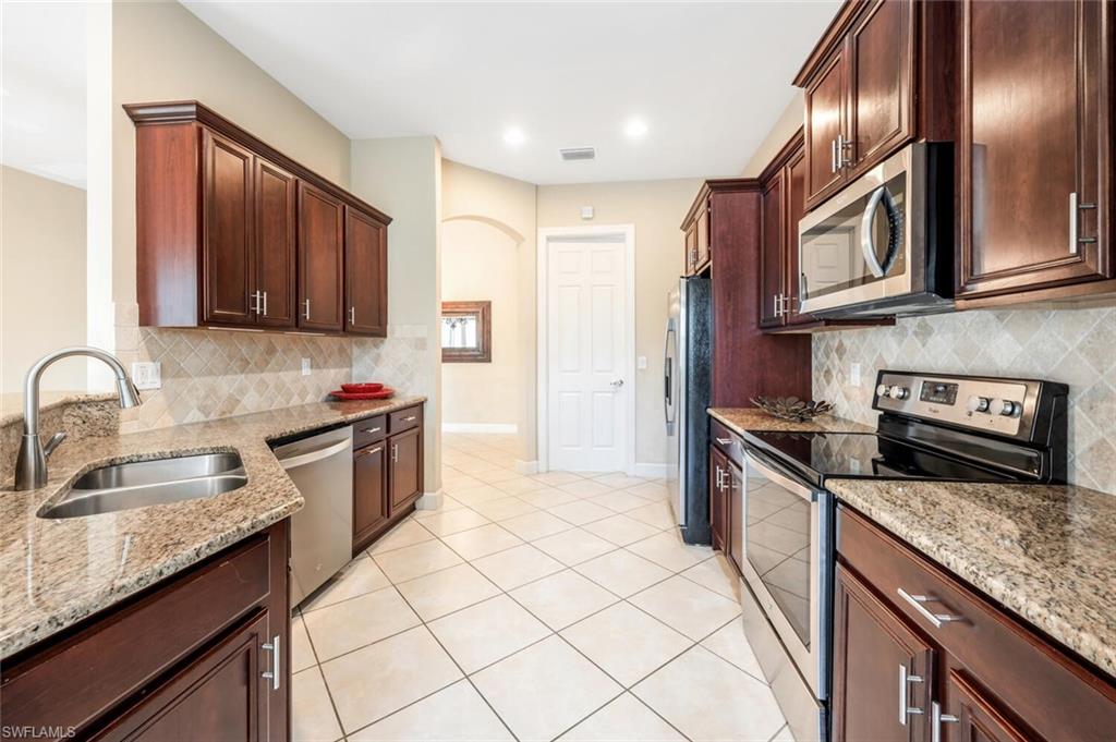 7975 Princeton Drive Naples, FL 34104 - Photo 4 of 28 a kitchen with stainless steel appliances granite countertop a sink stove and refrigerator
