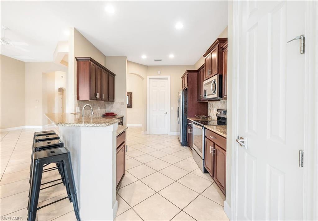 7975 Princeton Drive Naples, FL 34104 - Photo 5 of 28 a kitchen with cabinets and white appliances