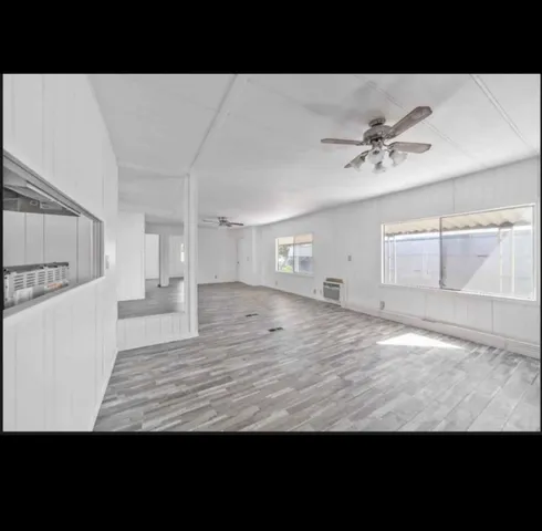 a view of empty room with wooden floor and ceiling fan