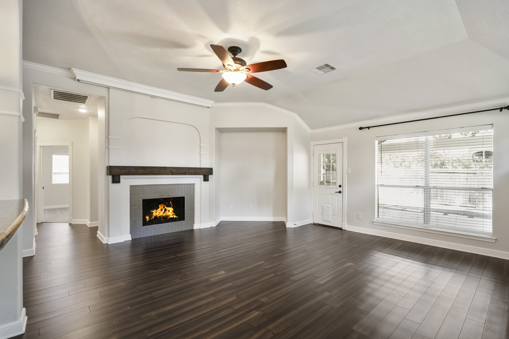 5802 Sawyer Bend Lane Spring, TX 77379 - Photo 14 of 50 an empty room with wooden floor a ceiling fan a fireplace and windows