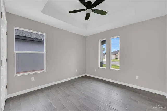 a view of an empty room with a window and wooden floor