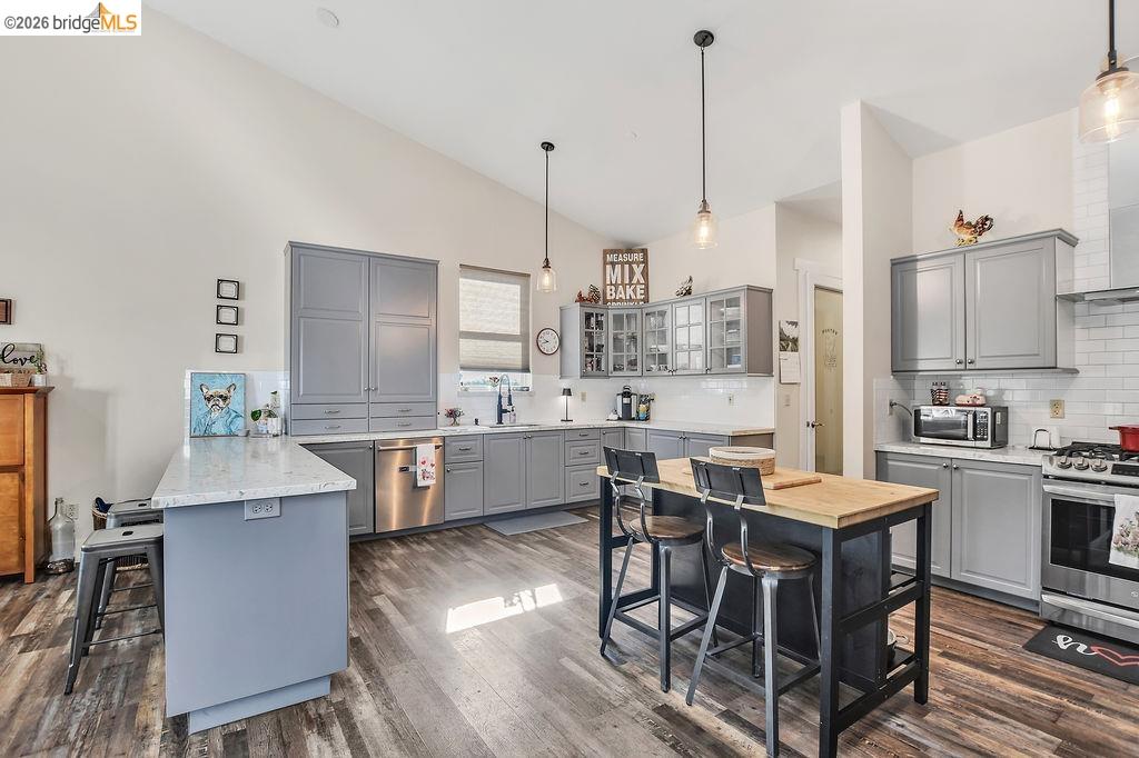 2200 Delta Road Knightsen, CA 94548 - Photo 8 of 26 Kitchen featuring a breakfast bar, gray cabinets, glass insert cabinets, stainless steel appliances, and vaulted ceiling