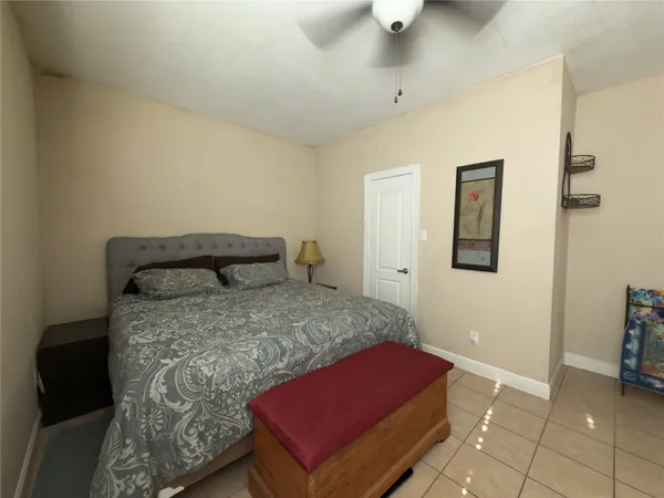 a bedroom with a bed and a potted plant on the dresser