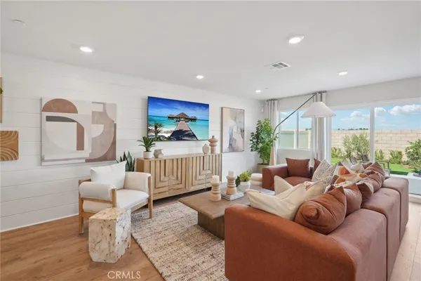 a living room with lots of furniture kitchen view and a potted plant