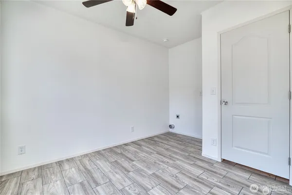 an empty room with a ceiling fan and wooden floor