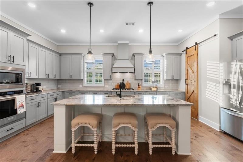 283 London Road Ball Ground, GA 30107 - Photo 21 of 73 a kitchen with kitchen island granite countertop a stove a sink and white cabinets with wooden floor