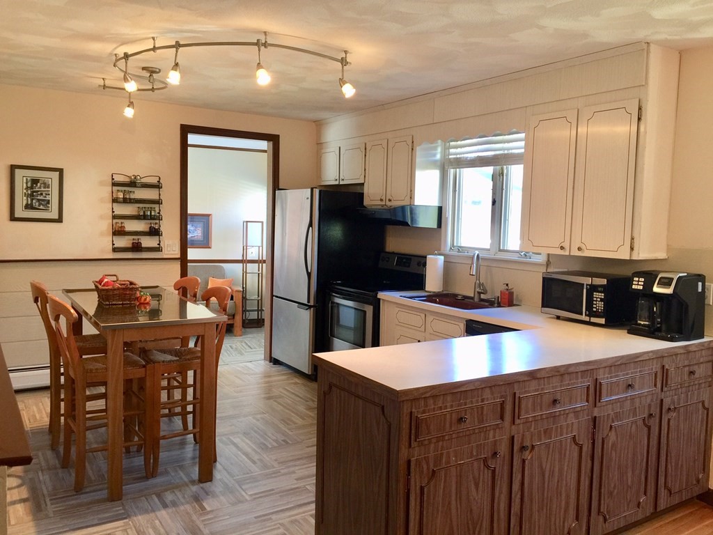 40 Niles Road Randolph, MA 02368 - Photo 7 of 29 a kitchen with stainless steel appliances granite countertop a table chairs sink refrigerator and microwave