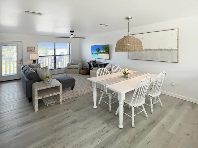 a dining room with wooden floor a chandelier a glass table and chairs
