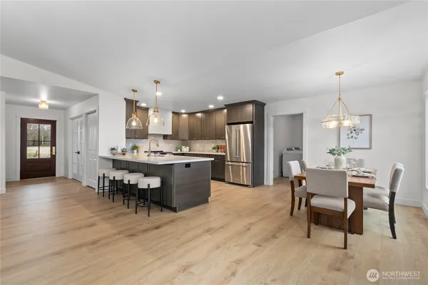 a large kitchen with stainless steel appliances kitchen island granite countertop a refrigerator a sink a stove and a wooden floors