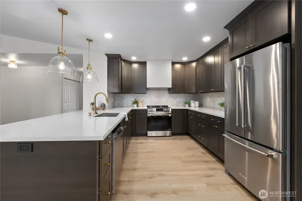 a large kitchen with granite countertop a stove top oven a sink a counter space and cabinets