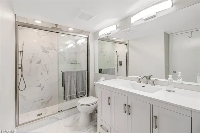 a bathroom with a shower sink vanity mirror and toilet
