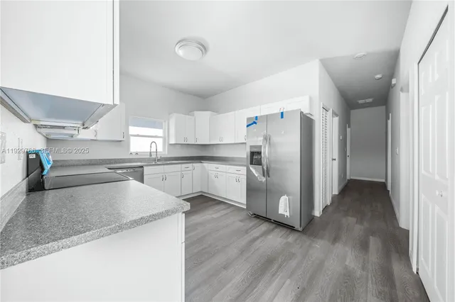 an empty room with wooden floor chandelier fan and windows