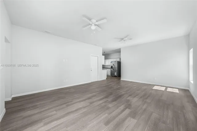 an empty room with wooden floor and a ceiling fan