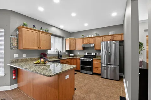 a kitchen with stainless steel appliances granite countertop a refrigerator a sink a stove a microwave and island