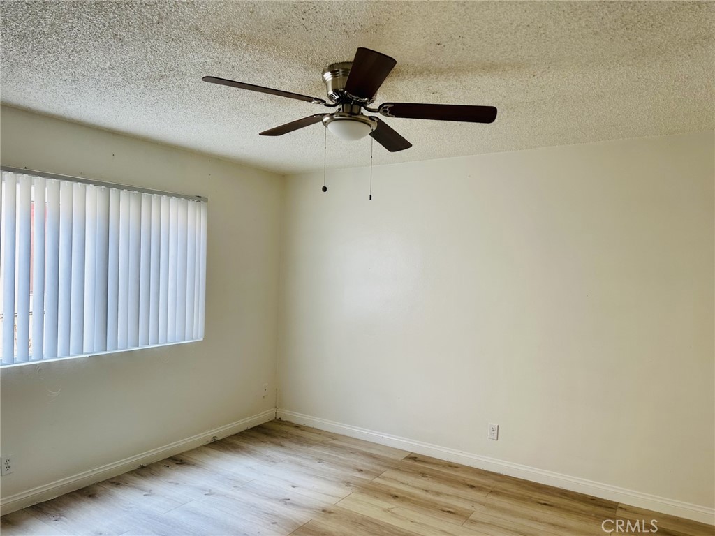 4830 Canoga Street, Unit E Montclair, CA 91763 - Photo 7 of 8 an empty room with wooden floor fan and windows