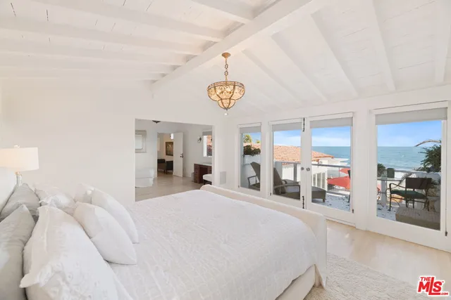 a bedroom with a bed and a large mirror with the kitchen view