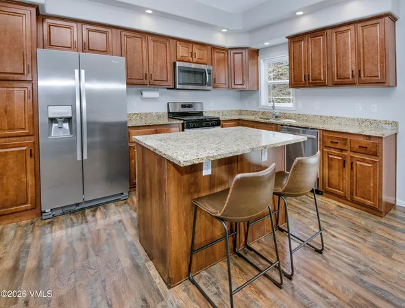 a kitchen with kitchen island granite countertop stainless steel appliances a sink a stove a refrigerator cabinets and dining table