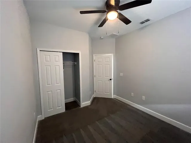 an empty room with closet and a ceiling fan
