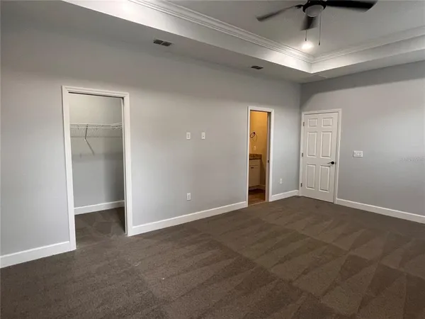a view of an empty room with window and chandelier fan