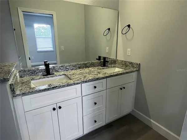 a bathroom with a granite countertop sink and a mirror