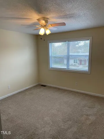 an empty room with a chandelier fan and a window