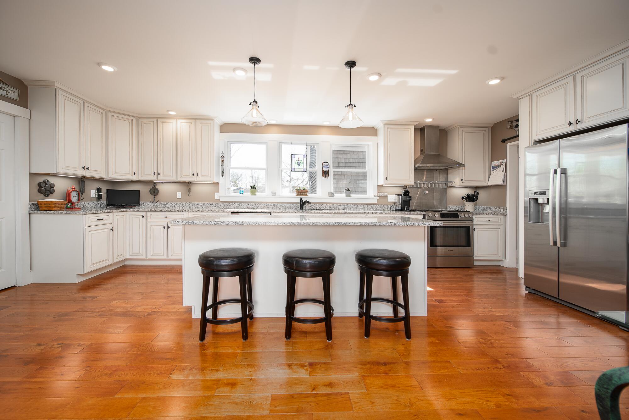 27 Watcha Path Edgartown, MA 02539 - Photo 7 of 24 a kitchen with stainless steel appliances granite countertop a stove a refrigerator a sink a stove and white cabinets with wooden floor
