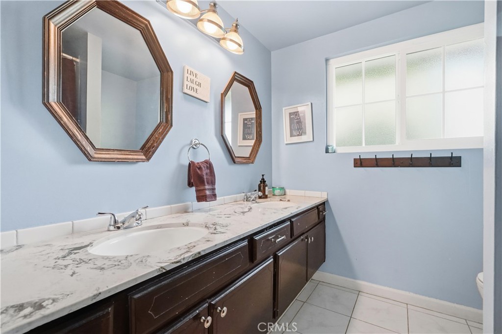 10808 Des Moines Avenue Porter Ranch, CA 91326 - Photo 26 of 39 a bathroom with a granite countertop toilet a sink and a mirror