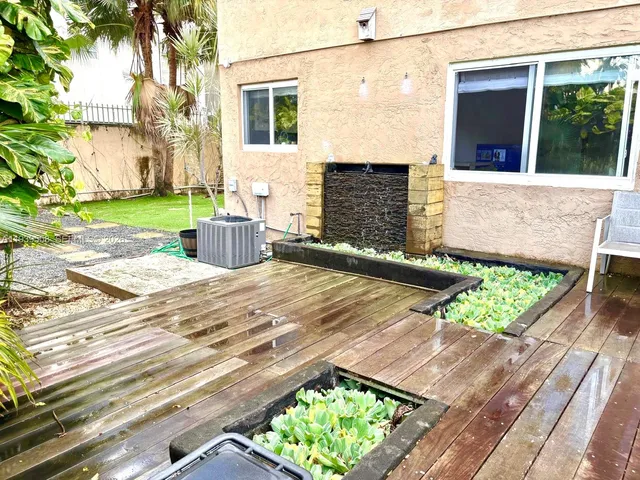 a view of a patio with table and chairs with wooden fence and large trees