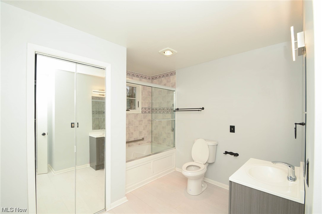 Full bathroom featuring tile floors, vanity, toilet, and shower / bath combination with glass door