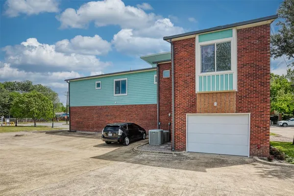 a view of a brick house with a yard large tree and plants