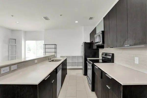 a kitchen with a sink a counter top space stainless steel appliances and cabinets
