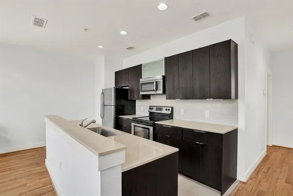 a kitchen with stainless steel appliances a sink dishwasher stove refrigerator and microwave with wooden floor