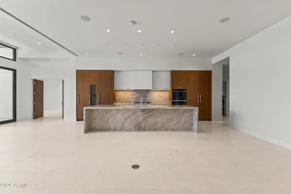 a large kitchen with stainless steel appliances a large counter top and a refrigerator