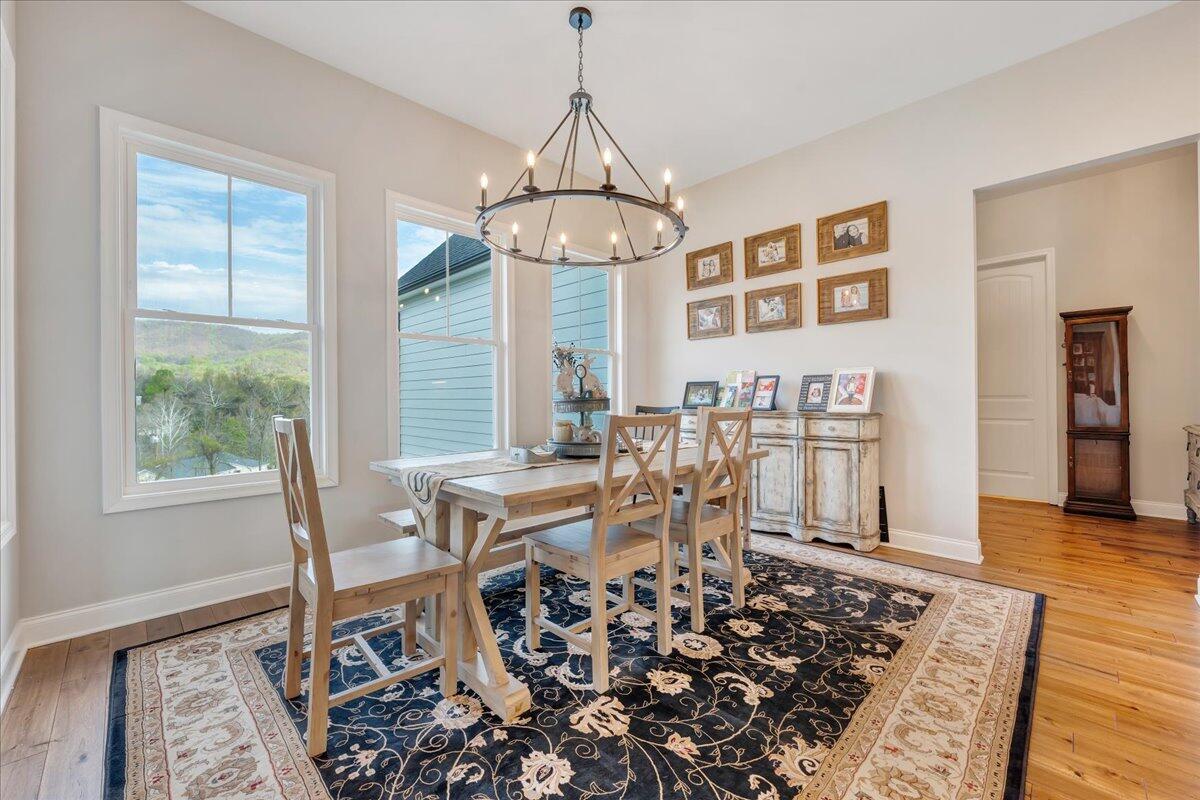 198 Thornblade Way Blue Ridge, VA 24064 - Photo 19 of 78 a dining room with wooden floor a chandelier a wooden table and chairs