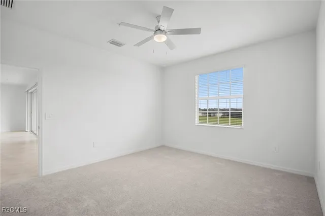 an empty room with a window and a ceiling fan