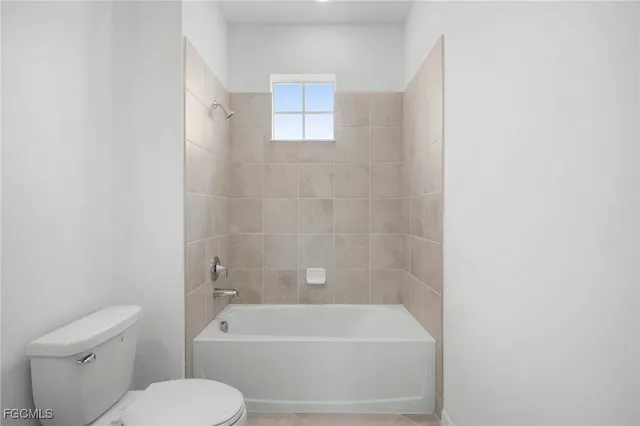 a bathroom with a toilet and white bath tub