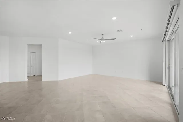 an empty room with a ceiling fan and window