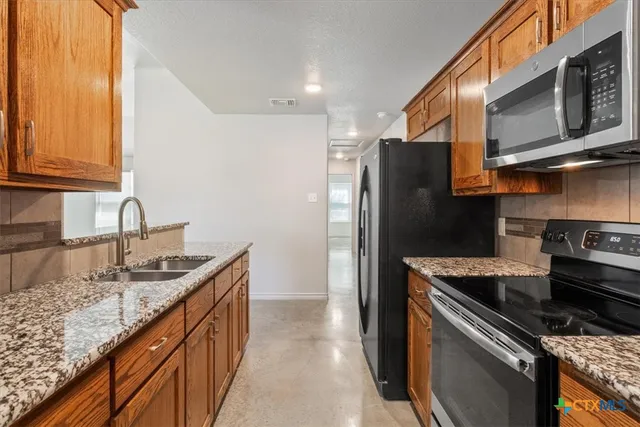 a kitchen with stainless steel appliances granite countertop a sink stove and refrigerator