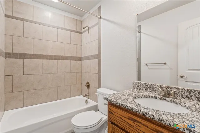 a bathroom with a granite countertop bathtub shower sink vanity mirror and toilet